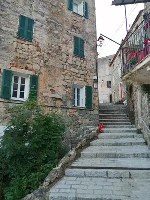 an old stone building with stairs and a balcony at Olmeto 10 mn plage App 5-6P in Olmeto