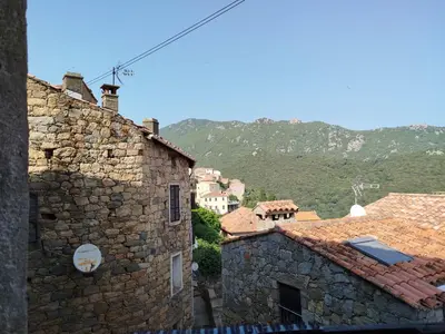 a view of a tile roof with mountains in the background at 10mn des plages - Olmeto village App 4P in Olmeto