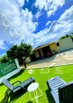 a lawn with two chairs and a table and a building at A casetta di l alivu in Lucciana