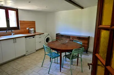 a kitchen with a table and chairs and a sink at A casetta di l alivu in Lucciana