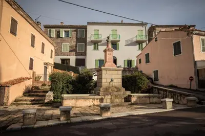 a statue in the middle of a street with buildings at Chambre de charme à Evisa in Evisa