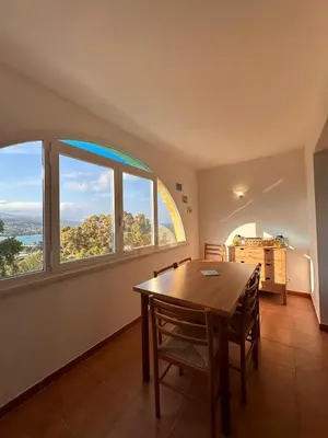 a dining room with a table and two windows at Appartement MAEVA duplex vue mer à Favone in Conca