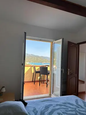 a bedroom with a door open to a balcony with a table at Appartement MAEVA duplex vue mer à Favone in Conca