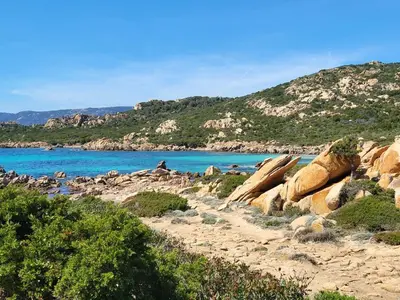 a beach with rocks and blue water and mountains at BandB les rosiers - chambre Garance in Conca