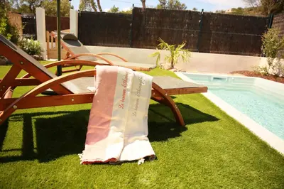 a towel sitting on a bench next to a swimming pool at Le Berceau d'Asciaghju Palombaggia - Accès plage et Piscine privée in Porto-Vecchio