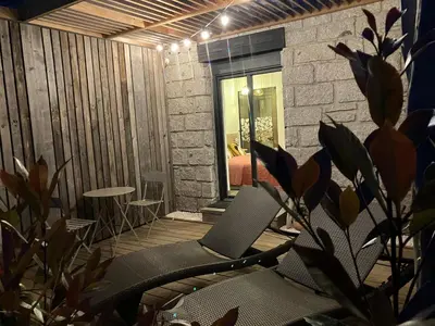 a patio with chairs and a table and a brick wall at Villa vue mer, jardin terrasse, parking privé à 300m du centre-ville de Porto-Vecchio in Porto-Vecchio
