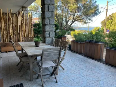 a wooden table and chairs on a patio at Villa vue mer, jardin terrasse, parking privé à 300m du centre-ville de Porto-Vecchio in Porto-Vecchio