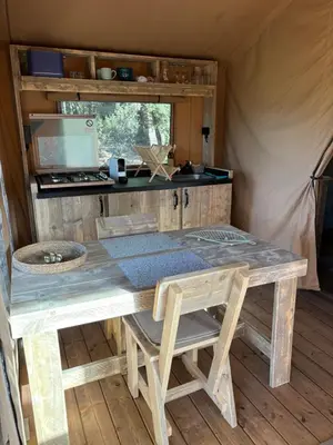 a table and chairs in a tent with a kitchen at Lodge A NASSA in Olivese