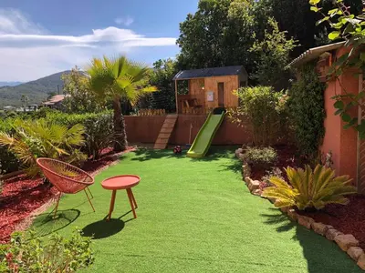 a yard with a green lawn with a slide at Villa Sì- Villa indépendante 3 chambres avec piscine et magnifique vue mer en plein centre de Porticcio in Porticcio