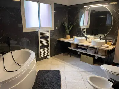 a bathroom with a tub and two sinks and a mirror at Villa Sì- Villa indépendante 3 chambres avec piscine et magnifique vue mer en plein centre de Porticcio in Porticcio