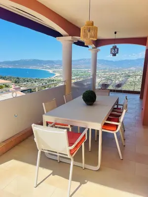 a dining room with a table and chairs on a balcony at Villa Sì- Villa indépendante 3 chambres avec piscine et magnifique vue mer en plein centre de Porticcio in Porticcio