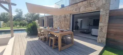 a wooden table with an umbrella on a patio at Bergerie Piana d'architecte neuve, 8 pers, piscine chauffée, à 10 min plage in Gialla
