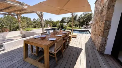 a wooden table with an umbrella on a deck at Bergerie Piana d'architecte neuve, 8 pers, piscine chauffée, à 10 min plage in Gialla