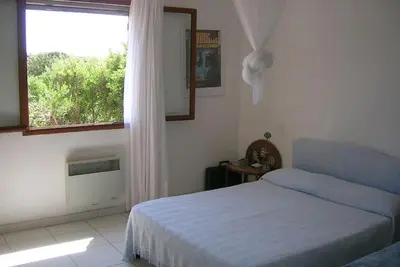 a white bedroom with a bed and a window at Villa pieds dans l'eau sur la plage in Pianottoli-Caldarello