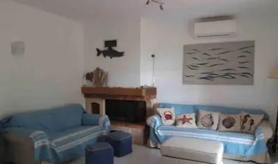 a living room with two blue couches and a fireplace at Villa pieds dans l'eau sur la plage in Pianottoli-Caldarello
