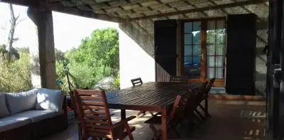 a wooden table and chairs on a patio with a couch at Villa pieds dans l'eau sur la plage in Pianottoli-Caldarello