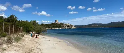 a group of people on a beach with a castle in the background at Villa pieds dans l'eau sur la plage in Pianottoli-Caldarello