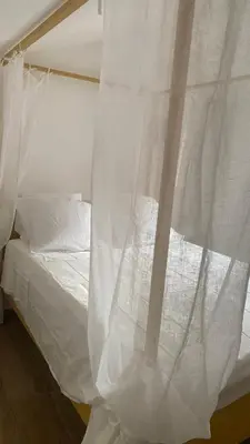 a white bed with a curtain hanging over it at A casa di Leia in Borgo