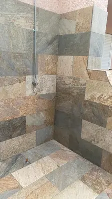 a bathroom with a shower with a stone wall at A casa di Leia in Borgo