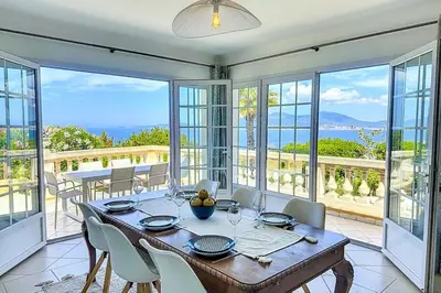 a dining room with a table and chairs and windows at Villa de Prestige - clim - vue mer panoramique - 8 pers - 4 chambres in Pietrosella