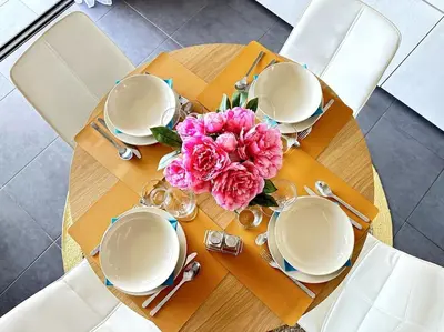 a table with plates and a vase of flowers on it at 5 min des plages - Appt 2 chambres A Casa Bella in Lucciana
