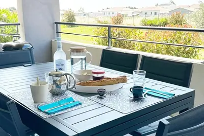 a table with a plate of food on a balcony at 5 min des plages - Appt 2 chambres A Casa Bella in Lucciana