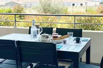 a table with a bottle of wine on a balcony at 5 min des plages - Appt 2 chambres A Casa Bella in Lucciana