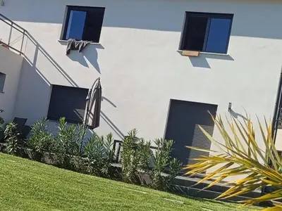 a white building with shuttered windows and plants at Doume et Coco T1 30M2 Vue mer in Taglio-Isolaccio