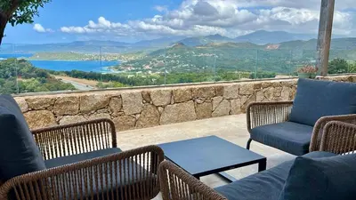 a patio with chairs and a table and a stone wall at Villa Toci in Calcatoggio