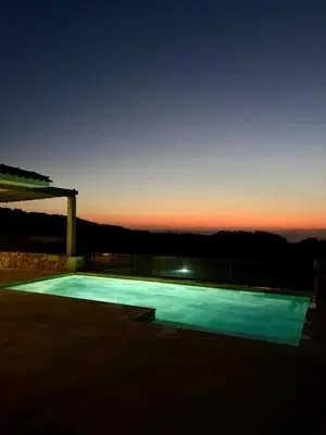 a swimming pool with a sunset in the background at Villa Toci in Calcatoggio