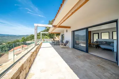 an outdoor patio with glass doors and a view at Villa Toci in Calcatoggio