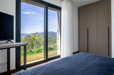a bedroom with a bed and a large window at Villa Toci in Calcatoggio