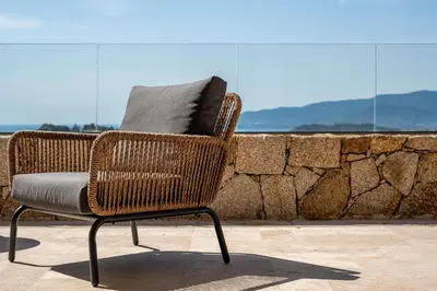 a wicker chair sitting on top of a stone wall at Villa Toci in Calcatoggio