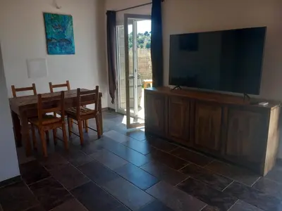 a living room with a large flat screen tv and a dining table at maison de vacances olmi cappella Corse in Olmi-Cappella