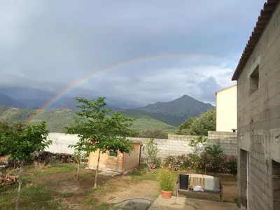 a rainbow in the sky over a yard with a house at maison de vacances olmi cappella Corse in Olmi-Cappella