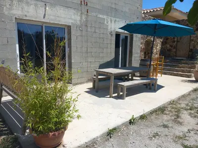 a table and bench with an umbrella next to a building at maison de vacances olmi cappella Corse in Olmi-Cappella