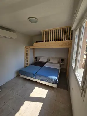 a bedroom with a bunk bed with a blue bedspread at Villa 7 personnes résidence Mélody in Santa-Maria-Poggio