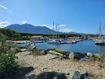 a group of boats docked in a marina with mountains at Villa 7 personnes résidence Mélody in Santa-Maria-Poggio