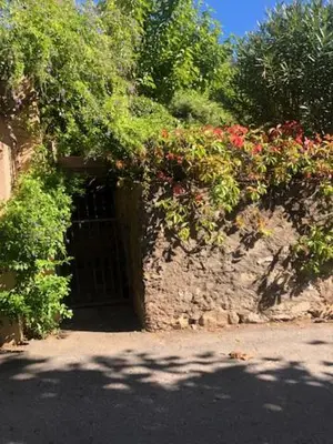 a door in a stone wall with flowers and plants at BandB les rosiers - Hellébore in Conca