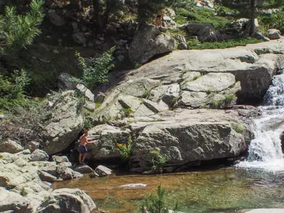 a person sitting on rocks next to a waterfall at Lemon in Casaglione