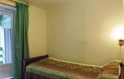 a bedroom with a bed with green curtains and a window at Nice Apartment In Sagone With Kitchen in Sagone