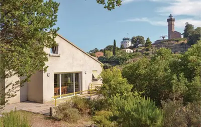 a white house on a hill with a lighthouse in the background at Cozy Home In San Giuliano With Wifi in San-Giuliano