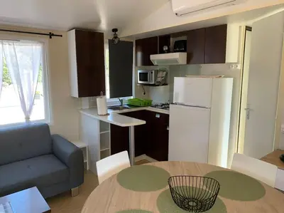 a small kitchen with a table and a refrigerator at Mobil- home à Calenzana in Calenzana