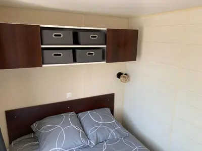 a bed with a wooden headboard with three drawers at Mobil- home à Calenzana in Calenzana