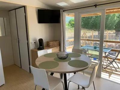 a dining room with a table and chairs and a balcony at Mobil- home à Calenzana in Calenzana