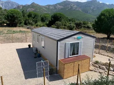 a tiny house in a field with mountains in the background at Mobil- home à Calenzana in Calenzana