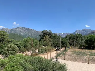 a person walking down a dirt road with mountains in the background at Mobil- home à Calenzana in Calenzana
