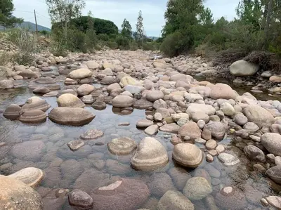 a river filled with rocks in a river of water at Mobil- home à Calenzana in Calenzana