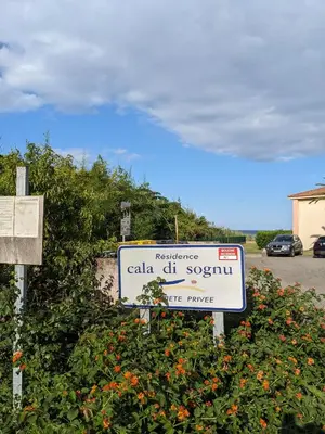 a sign in front of a bush with flowers at Vue sur mer cala Di sognu in San-Nicolao