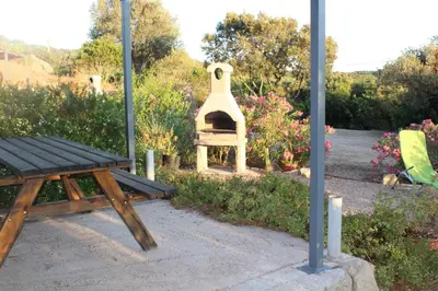 a picnic table and a pizza oven in a garden at Petit chalet in Pianottoli-Caldarello